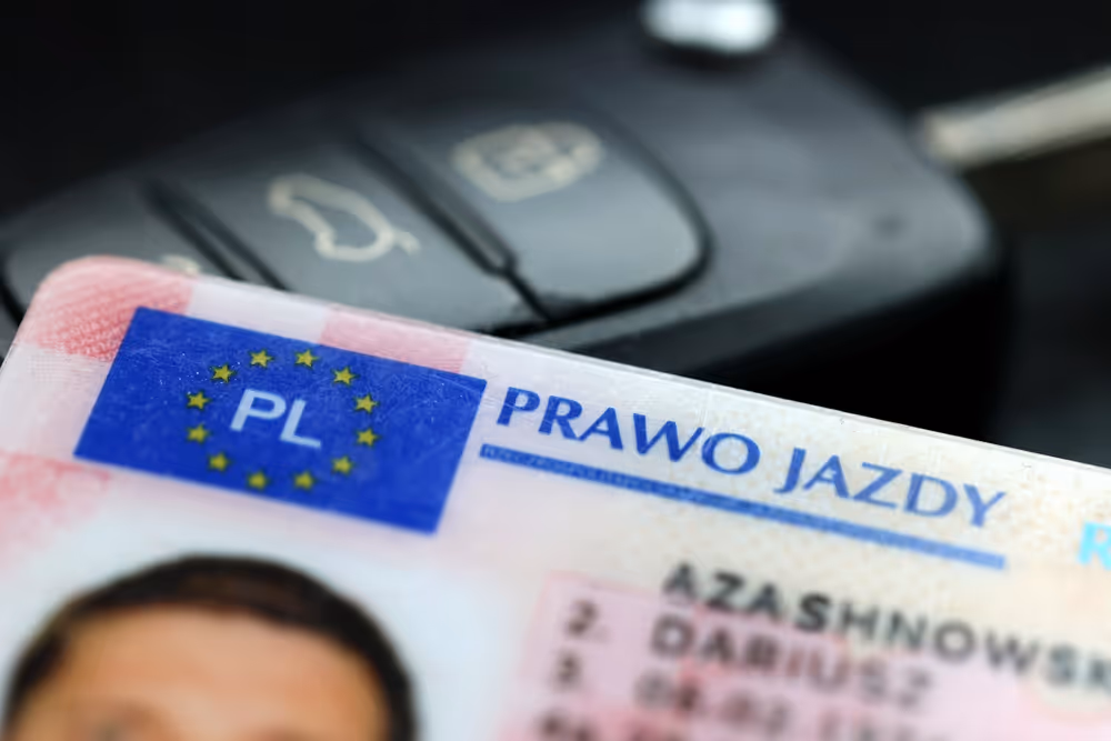 Close-up of a Polish driving license card with the EU and PL symbol, the words 'PRAWO JAZDY', and a blurred car key in the background.